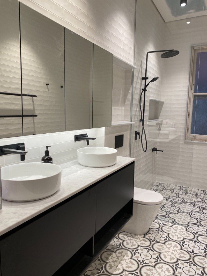 A dreary 1970s bathroom, opened up to fit a large shower, a separate bath, a double vanity and plenty of storage, with heated floors and towel rails.