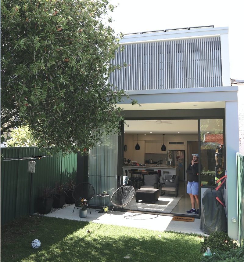 The same extension built, seen from the same spot in the garden, with the owner standing in the open doorway