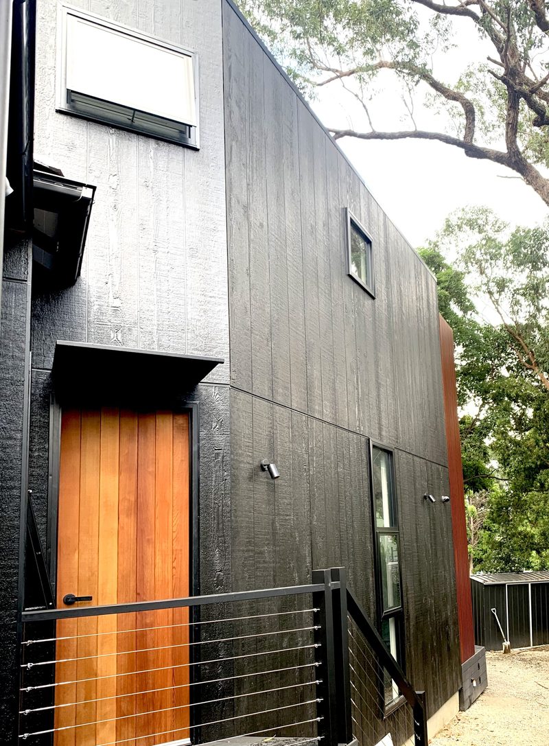The back door. Natural timbers in contrast, from the varnished red cedar door to the charred timber weatherboards, make the entry easy to find from the rear.