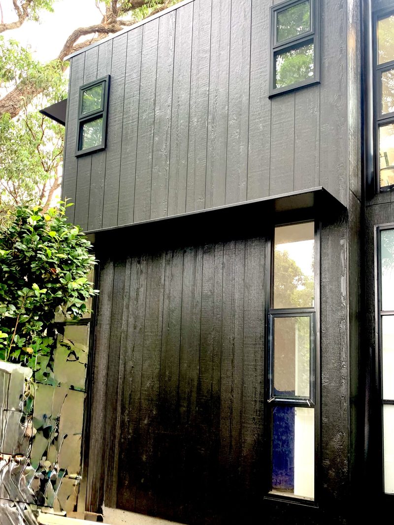 Dark charred timber lets the addition blend into the shadows of the existing trees.