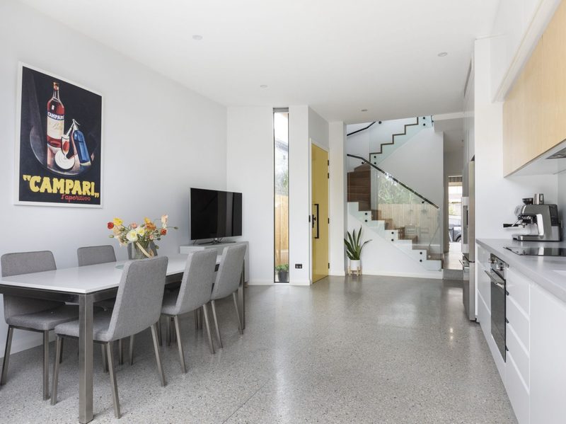 Looking from the garden through the kitchen and dining space to the new entry. The stairs lead up to three bedrooms and a bathroom, and a side passage leads to the laundry, toilet, and a private living room, the family’s quiet retreat.