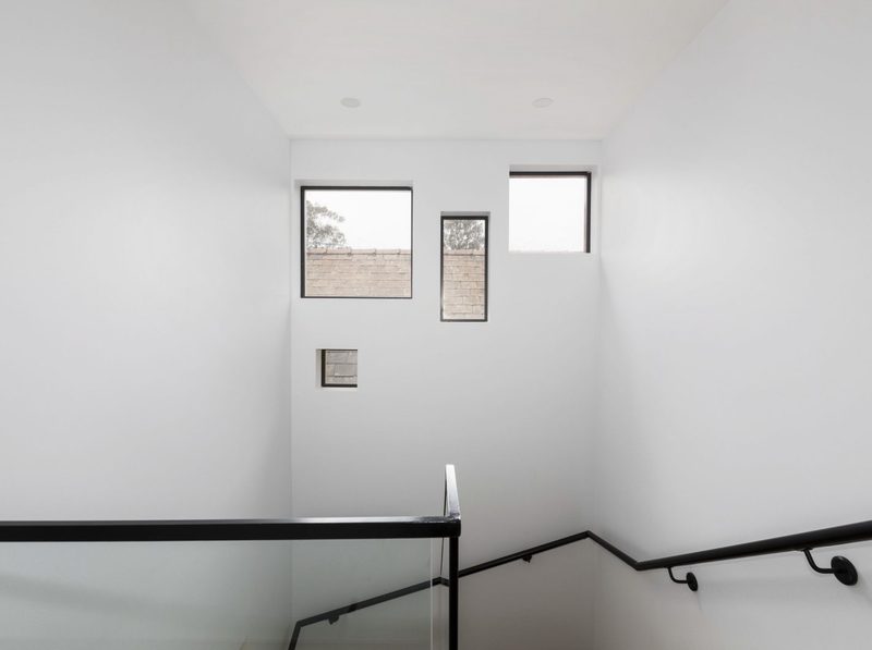 The stairwell between the ground and first floors is lit by seemingly random windows that bring in daylight while keeping privacy.