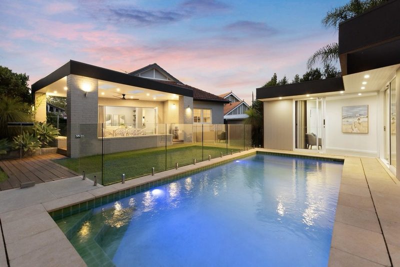 Contemporary pavilion and swimming pool lit at twilight, with the original tiled gable of the bungalow behind, Roseville