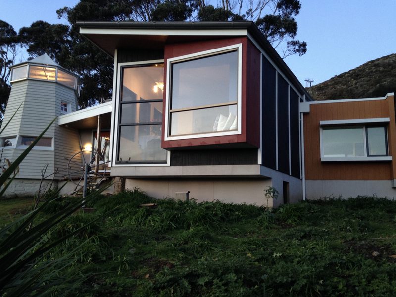 The living room projects straight out, with a bay window and window seat set for enjoying the view. It’s cantilevered off the main facade, which is itself cantilevered off the rest of the structure to minimise its impact on the site. The tiny pop-out to the right is the inglenook: just big enough for a queen-size bed, with a ceiling as low as was legally permissible, and purely a place of rest, with views to The Nut on one side and Gordon’s Bay on the other.